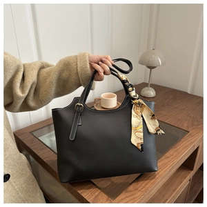 Detail of black tote bag with white contrast stitching and silk scarf handle decor