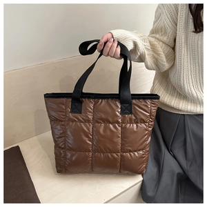 Gros plan du sac fourre-tout matelassé marron montrant le tissu brillant et les coutures
