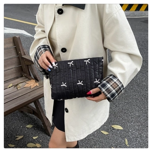 Bolso acolchado negro con bordado blanco llevado por una modelo al aire libre