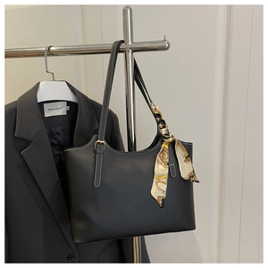 Detail of a black leather tote bag with a patterned silk scarf on the handle
