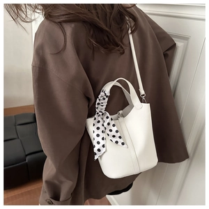 Detail of white lychee leather bucket bag with polka dot silk scarf and adjustable strap