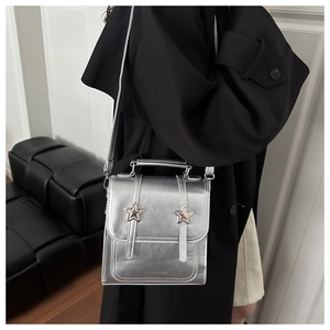 Vue latérale du sac bandoulière argenté métallisé avec étoiles sur un manteau noir