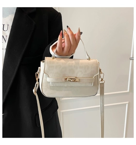 Detail of cream leopard embossed PU leather handbag with golden twist lock on black coat