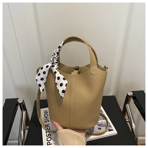 Detail of khaki pebbled leather bucket bag with silk scarf on handle and metal buckle