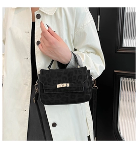 Detail of black leopard print crossbody bag with gold twist lock on a beige trench coat
