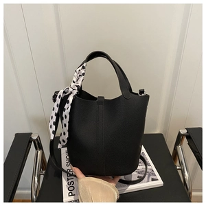Detail of black lychee grain leather bucket bag featuring a polka dot silk scarf handle