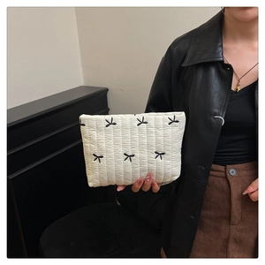 Detalle de la tela de nailon acolchada blanca con bordado de lazos negros en el bolso