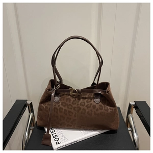 Détail d'un sac cabas léopard avec boucle dorée posé sur un fauteuil en cuir
