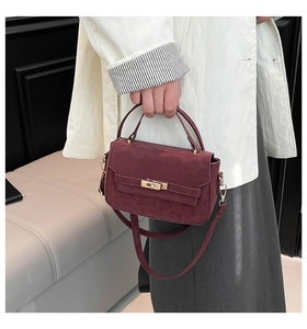 Close-up of burgundy leopard print handbag with golden turn-lock and leather handle