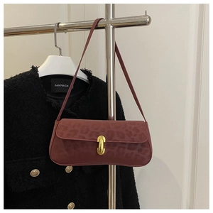 Detail of burgundy leopard embossed handbag with elegant gold metal buckle clasp