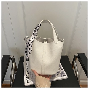 Detail of white lychee grain bucket bag featuring a polka dot silk scarf wrapped handle