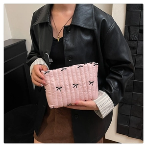 Neceser acolchado rosa con lazos negros bordados mostrado con un conjunto de moda