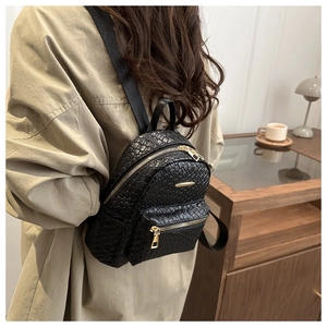 Detail of black woven PU leather mini backpack with gold zippers and nylon straps