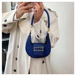 Detail of blue lizard pattern PU leather bag with gold hardware on a beige coat background
