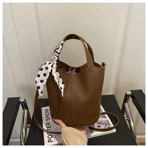 Detail of brown litchi pattern bucket bag with polka dot scarf on handle