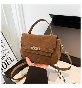 Close-up of brown leopard pattern handbag with golden metal twist lock and suede texture
