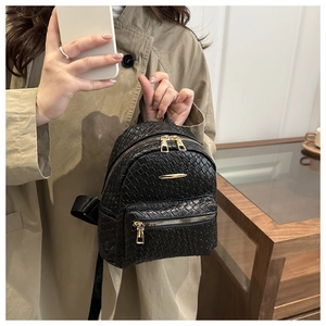 Detail of black woven texture PU leather backpack with gold zippers and metal bar accent