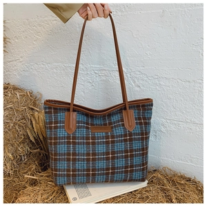 Détail du sac cabas en tweed à carreaux bleu et marron avec lanières en cuir et logo