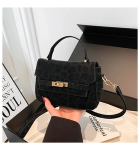 Detail of black leopard print handbag with golden twist lock and matte texture surface