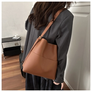 Brown leather bucket bag detail with contrast stitching and adjustable gold buckle strap