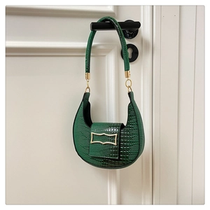 Detail shot of green crocodile textured faux leather crescent bag with gold buckle