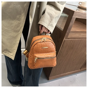 Close-up of tan woven texture and gold zipper details on a chic women's mini backpack