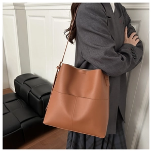 Detail of caramel leather bucket bag with cross stitching on minimalist exterior