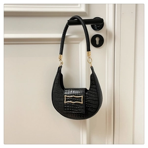 Detail of black faux crocodile leather crescent bag with elegant gold metal clasp