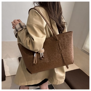 Brown leopard print tote bag shown on shoulder with plush pendant and ribbon detail