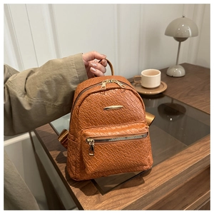 Detail of caramel brown woven PU leather backpack with gold hardware and front pocket