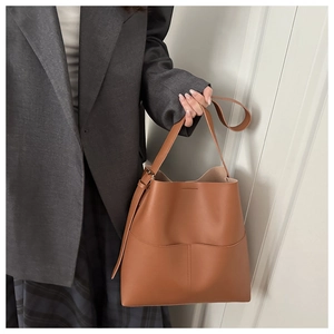 Detail of caramel leather bucket bag featuring vertical stitching and adjustable strap