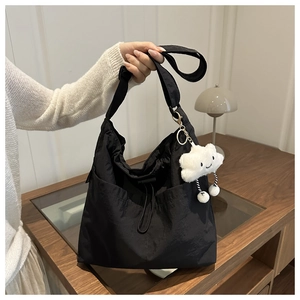 Nahaufnahme der schwarzen Nylon-Tasche mit Kordelzug und weißem Plüsch-Wolkenanhänger
