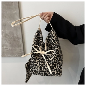 Detail of leopard print tote bag featuring a beige ribbon bow and matching mini pouch