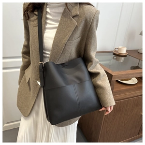 Detail of large black bucket bag with crossbody strap and front pocket stitching