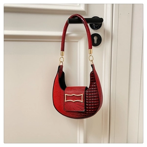Detail of red crescent bag featuring crocodile embossed leather and gold buckle