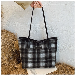 Détail d'un sac cabas en tweed à carreaux avec lanières en cuir sur un fond esthétique vintage