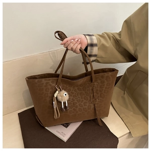 Detail of vintage leopard print tote bag with brown handles and plush charm accessory