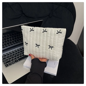 Detalle de un bolso de mano acolchado blanco con elegantes bordados de lazos negros