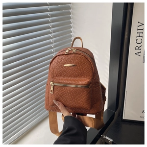 Detailed close-up of brown woven PU leather backpack with gold zippers and metal accents