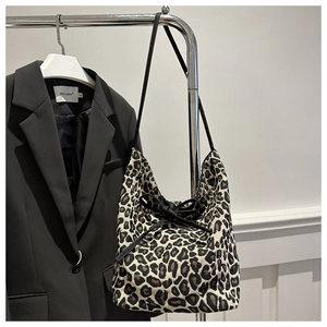 Detail of leopard print tote bag with black drawstring hanging on a metal rack