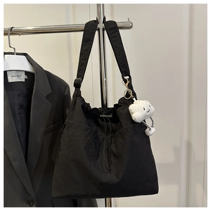 Detail einer schwarzen Nylon-Tasche mit Kordelzug und weißem Plüsch-Wolkenanhänger