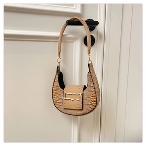 Detail of minimalist beige croissant bag with crocodile embossed texture and gold metal clasp