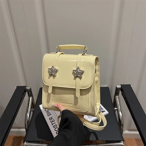 Petit sac à dos jaune crème minimaliste avec boucles étoiles sur siège en cuir