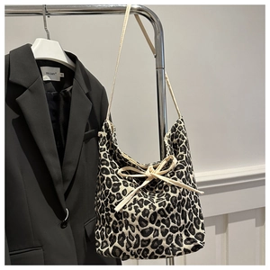 Detail view of leopard print tote bag featuring cream drawstring bow and woven strap