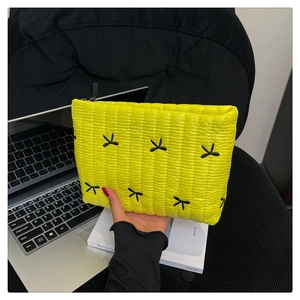 Detalle del bolso acolchado amarillo con lazos negros y textura ligera