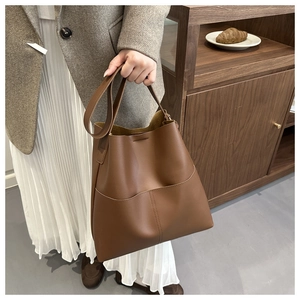 Close-up of brown leather bucket bag with curved pocket and elegant stitching detail