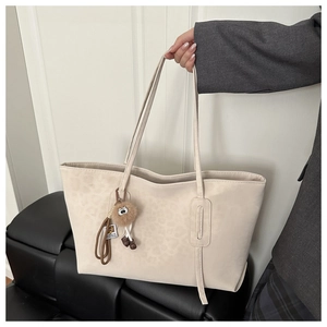 Detail of large beige leopard print tote bag featuring a fluffy eye charm and sleek straps