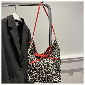 Leopard print canvas tote bag featuring a bright red bow and matching shoulder strap
