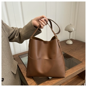 Detail view of a large brown leather bucket bag with front pocket for daily commute