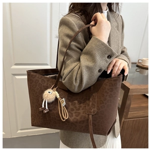 Detail of vintage leopard print tote bag with brown straps and cute plush pendant